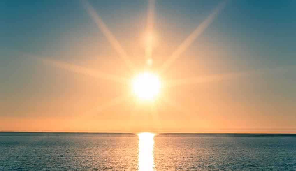 A serene sunrise over a calm ocean with vibrant colors in the sky