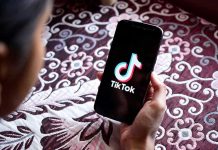 Hand holding phone showing TikTok logo.