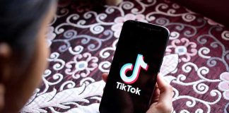 Hand holding phone showing TikTok logo.