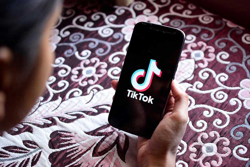 Hand holding phone showing TikTok logo.