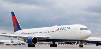 Delta Airlines airplane on airport runway, cloudy sky.