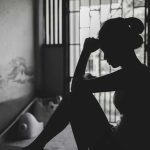 Silhouetted person sitting by a window, deep in thought.