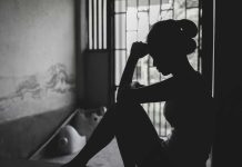 Silhouetted person sitting by a window, deep in thought.