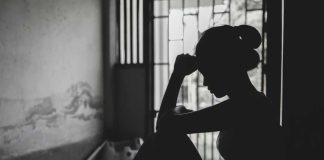 Silhouetted person sitting by a window, deep in thought.