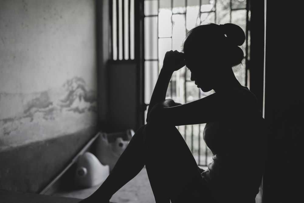 Silhouetted person sitting by a window, deep in thought.