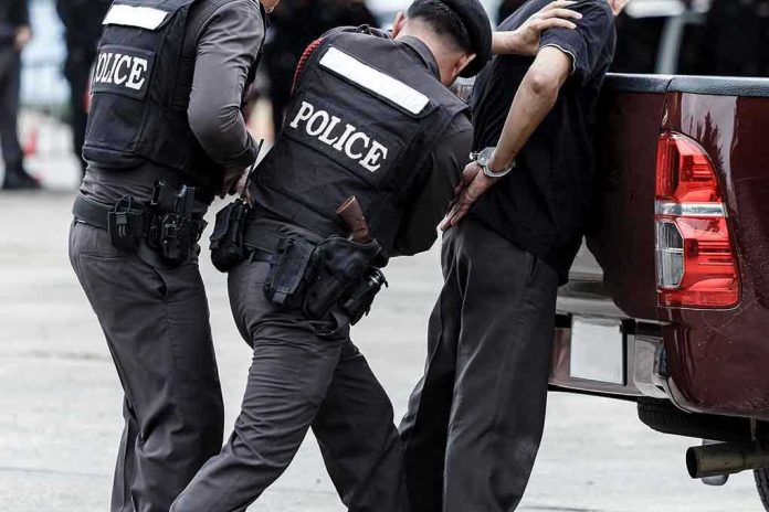 687629158 Police officers arresting a handcuffed person.