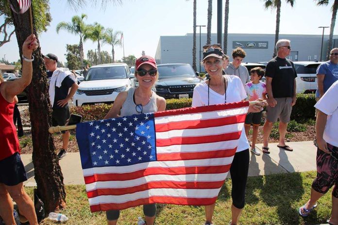 shutterstock_1836865666.jpg Two women holding an American flag at a community event