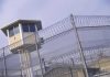 Guard tower behind barbed wire fence in a prison.