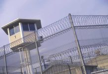 Guard tower behind barbed wire fence in a prison.