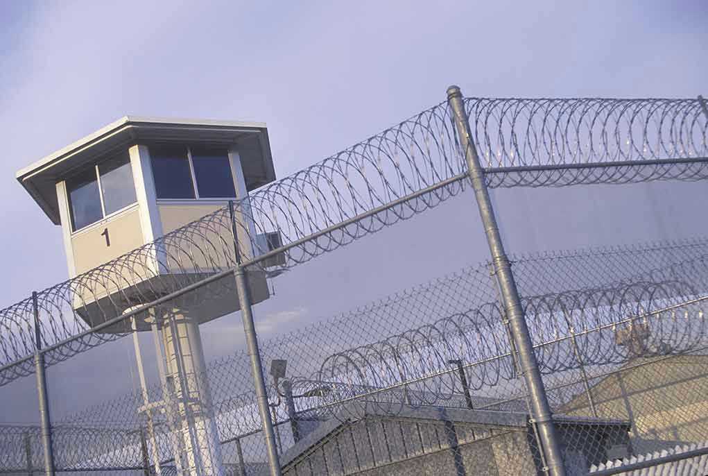 Guard tower behind barbed wire fence in a prison.