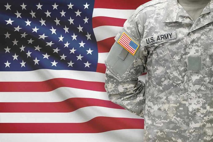 247938520 Soldier in camouflage uniform standing before American flag.