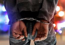 NBA Coach ARRESTED – Mafia Ties Revealed! Person in handcuffs with colorful lights in background.