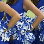 Cheerleaders in blue and white uniforms holding pom poms