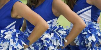 Cheerleaders in blue and white uniforms holding pom poms