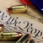 Close-up of bullets surrounding a historical document with the phrase We the People