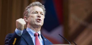 Man in a suit passionately delivering a speech at a podium