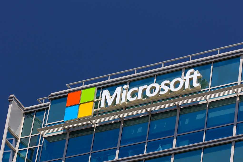 Microsoft logo on a modern corporate building against a blue sky