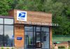 Exterior view of a modern United States Post Office building surrounded by greenery
