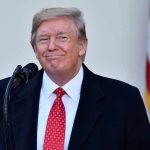 Man in suit and tie speaking at podium.
