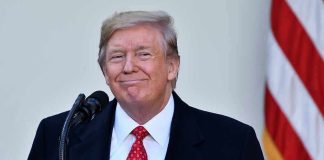 Man in suit and tie speaking at podium.
