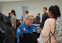 TSA Bonuses: Noem Shocks with Generous Move TSA agent checks passengers documents at airport security.