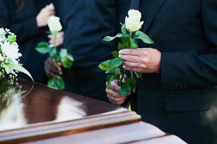 Mourners holding white roses by a casket.