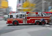 Red fire truck driving through city street crosswalk