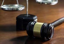 Gavel and scales of justice on wooden table.