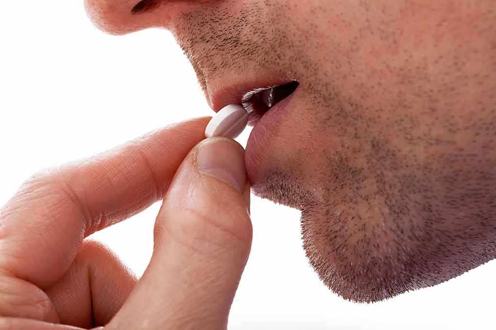 Close up of a man preparing to take a pill