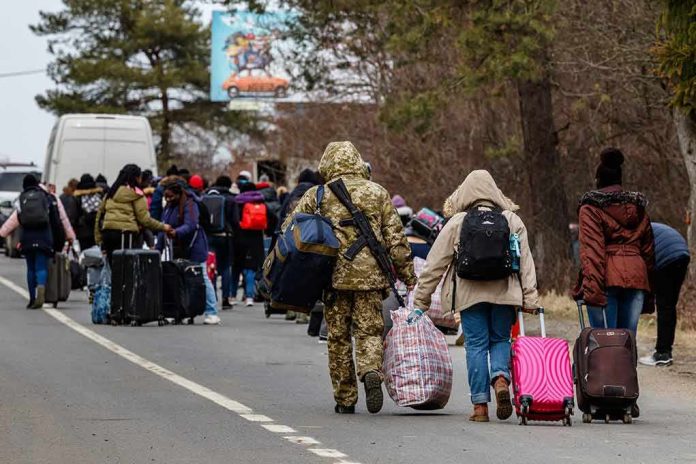 shutterstock_2131281067 (2).jpg Group of people carrying luggage walking along a road with a soldier