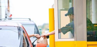 Customer receiving a food order at a drive-thru window