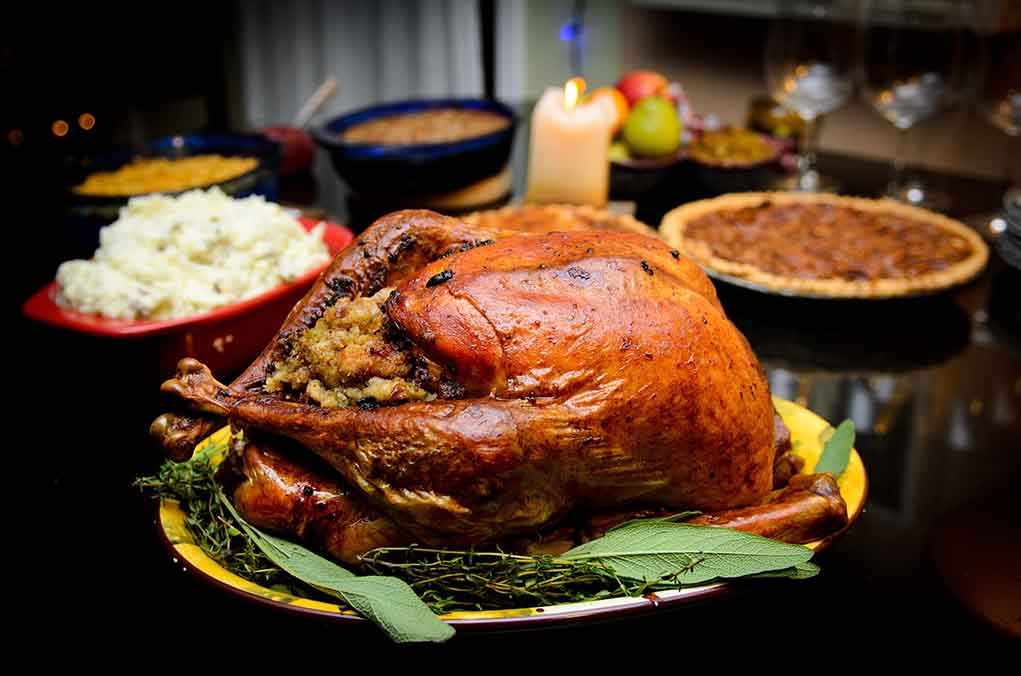 A beautifully roasted turkey on a festive table surrounded by side dishes and decorations