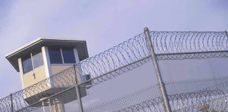 Guard tower behind barbed wire fence in a prison.