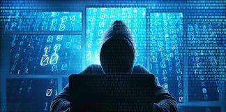 Person in hoodie using a laptop with digital code.