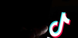 Finger pointing at TikTok logo on a screen.