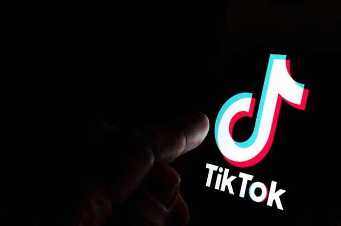 1540774727 Finger pointing at TikTok logo on a screen.