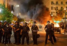 Entire Government Cabinet RESIGNS – European Protests Erupt! Police officers in riot gear near burning car.