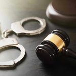 Handcuffs and judges gavel on the table.