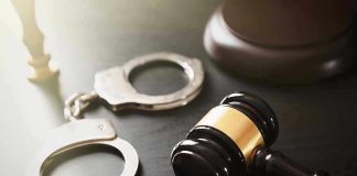 Handcuffs and judges gavel on the table.