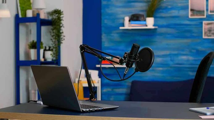 Laptop and a microphone on a desk.