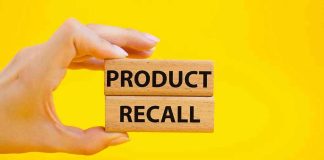 Hand holding Product Recall blocks on yellow background.