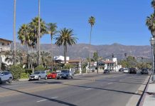 SHOCKING Attack Rocks Jewish Neighborhood Street with cars, palm trees, and mountains in the background.