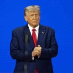 Wall Street Attacks Trump’s Fed Pick – High Stakes! Man in a suit with a blue background.