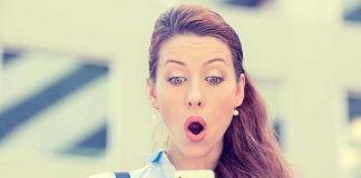 Surprised woman looking at her smartphone outdoors