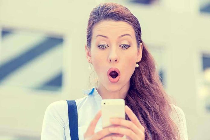 237618796 Surprised woman looking at her smartphone outdoors