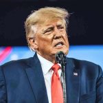 Trump OBLITERATES Ghetto Congresswoman’s Senate Ambitions Man in suit speaking at a microphone.