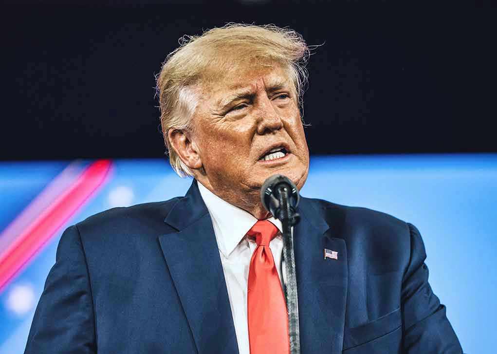 Man in suit speaking at a microphone.