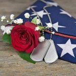Dog tags, red rose, and folded American flag.