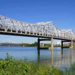 Trooper’s Daring Bridge Rescue – Unbelievable! A large metal bridge spanning over a river with a clear blue sky in the background