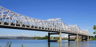 A large metal bridge spanning over a river with a clear blue sky in the background